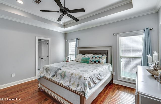 bedroom with dark wood-type flooring, ceiling fan, ornamental molding, and a raised ceiling