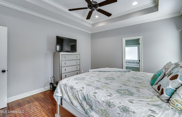 bedroom featuring a raised ceiling, crown molding, dark wood-type flooring, and ceiling fan