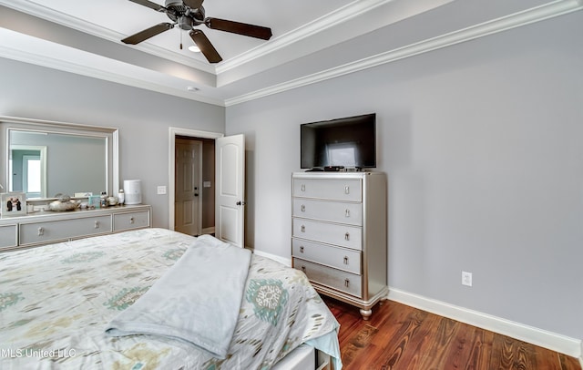 bedroom with dark wood-type flooring, ceiling fan, ornamental molding, and a raised ceiling