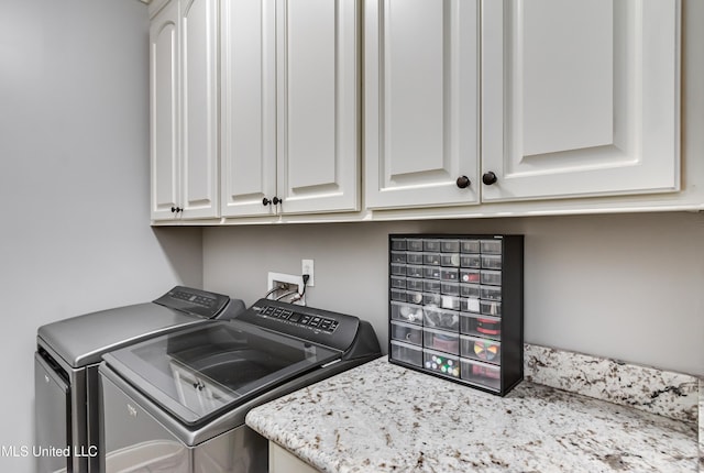 clothes washing area with cabinets and washing machine and clothes dryer