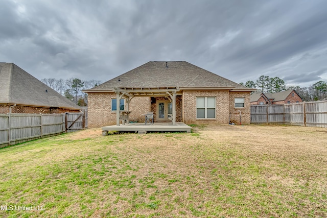 rear view of house with a pergola, a lawn, and a deck