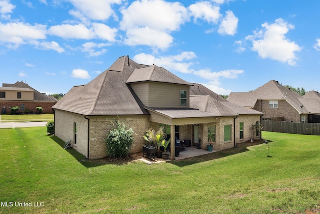rear view of house with a patio, fence, a yard, and brick siding