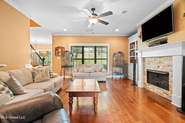 living room with a fireplace, wood-type flooring, stairs, a ceiling fan, and visible vents
