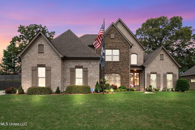 view of front of home with brick siding, a shingled roof, and a yard