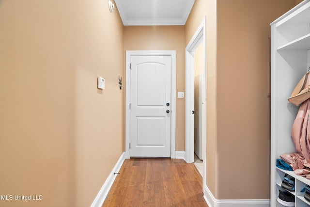 doorway featuring crown molding, baseboards, and wood finished floors