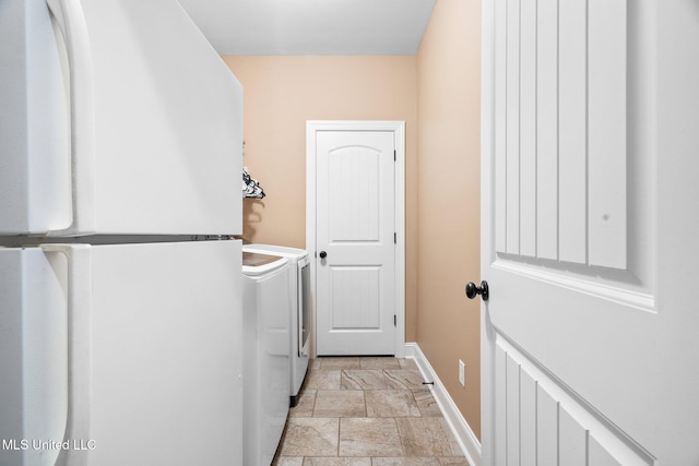 laundry area featuring laundry area, stone finish flooring, baseboards, and washer and dryer