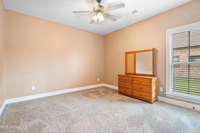 carpeted empty room featuring baseboards, ceiling fan, and visible vents