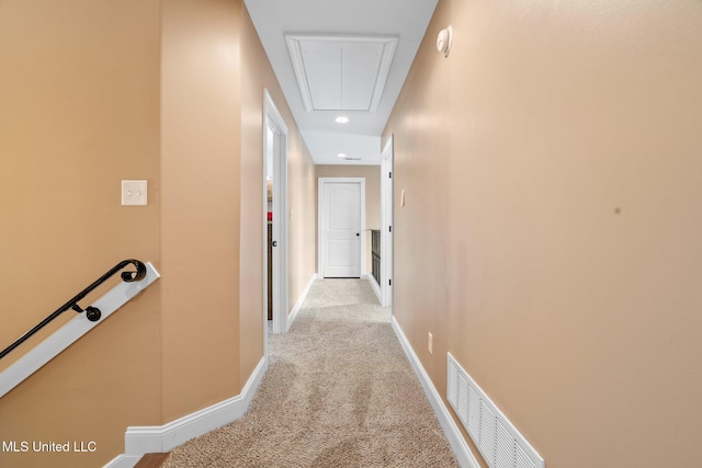 hall featuring attic access, light colored carpet, visible vents, baseboards, and an upstairs landing