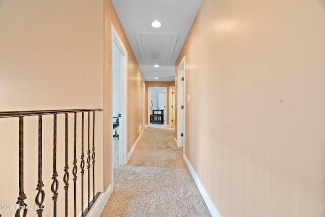 hallway featuring light colored carpet, attic access, baseboards, and recessed lighting