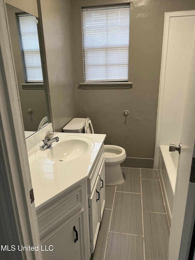 bathroom with vanity, toilet, and a washtub