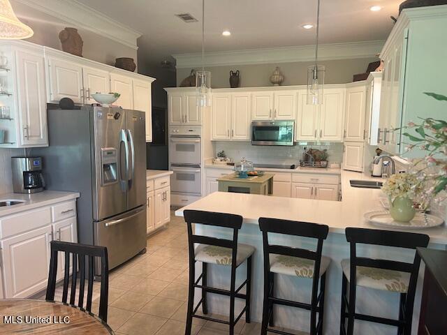 709 Oak Trl, Canton, MS 39046 - kitchen with appliances with stainless steel finishes, tasteful backsplash, a peninsula, light countertops, and decorative light fixtures