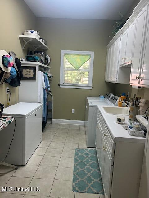 709 Oak Trl, Canton, MS 39046 - laundry area featuring cabinet space, washer and dryer, and light tile patterned floors