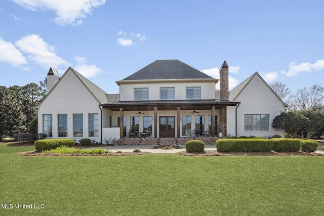 back of house featuring a standing seam roof, a yard, metal roof, ceiling fan, and a chimney