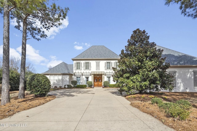 view of front of house featuring stucco siding, roof with shingles, and concrete driveway