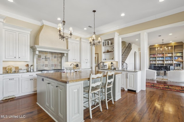 kitchen with an inviting chandelier, custom exhaust hood, dark wood-style flooring, and open shelves