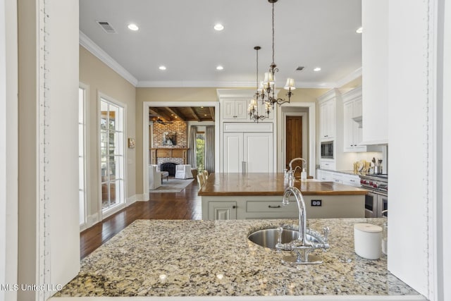 kitchen with dark wood-type flooring, ornamental molding, range with two ovens, white cabinetry, and a sink