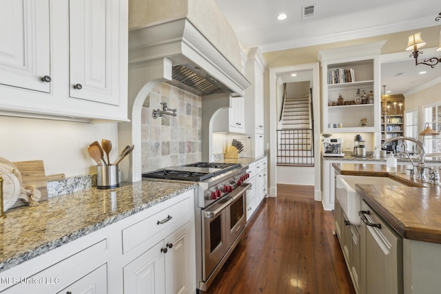 kitchen with visible vents, custom range hood, dark wood finished floors, butcher block counters, and range with two ovens