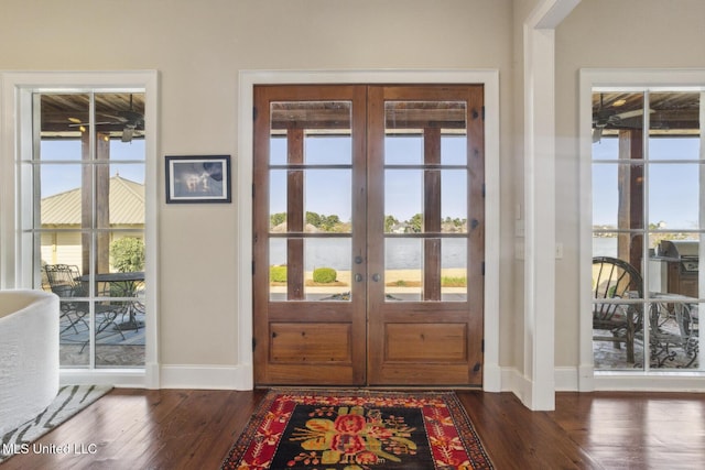 doorway featuring french doors, a water view, baseboards, and dark wood-style flooring