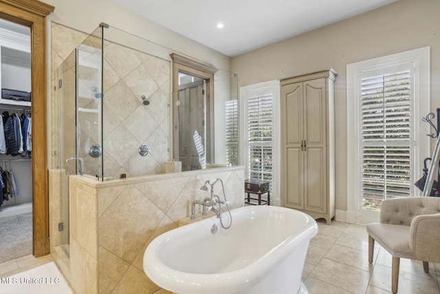 bathroom with a walk in closet, a stall shower, recessed lighting, tile patterned flooring, and a freestanding bath