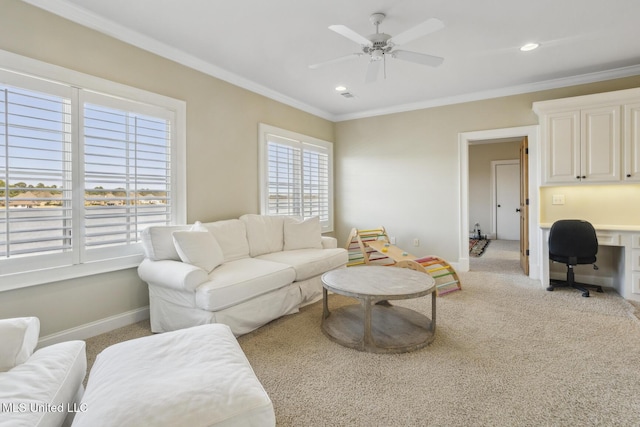 carpeted living room featuring ornamental molding, a ceiling fan, built in desk, recessed lighting, and baseboards