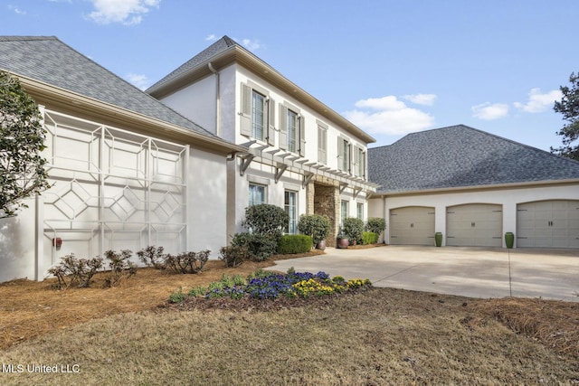 view of front facade with stucco siding, concrete driveway, a garage, and a shingled roof