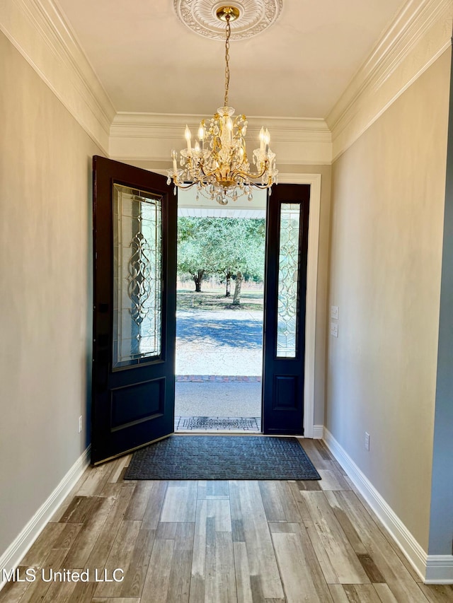 foyer with hardwood / wood-style floors, ornamental molding, and a chandelier