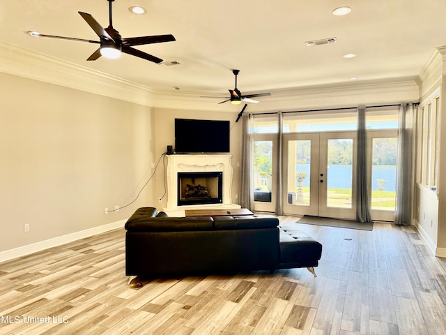 living room featuring ceiling fan, french doors, crown molding, and light hardwood / wood-style flooring