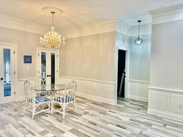 dining room with light wood-type flooring, ornamental molding, and a chandelier