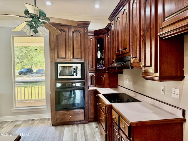 kitchen featuring a healthy amount of sunlight, light hardwood / wood-style flooring, black appliances, and ornamental molding