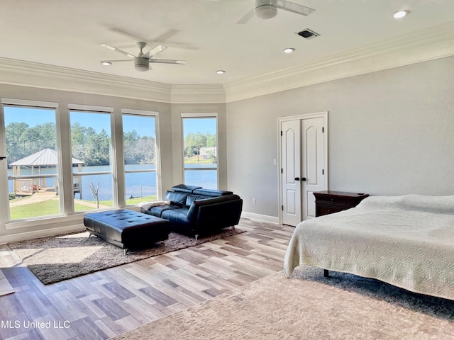 bedroom featuring a water view, light hardwood / wood-style flooring, ceiling fan, and ornamental molding