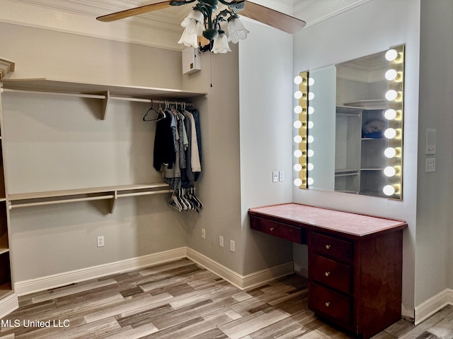 walk in closet featuring ceiling fan, built in desk, and light wood-type flooring