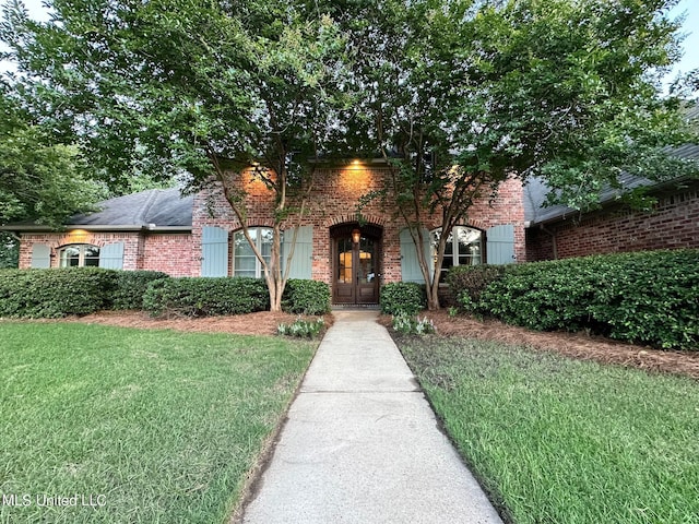 tudor house featuring a front lawn and brick siding