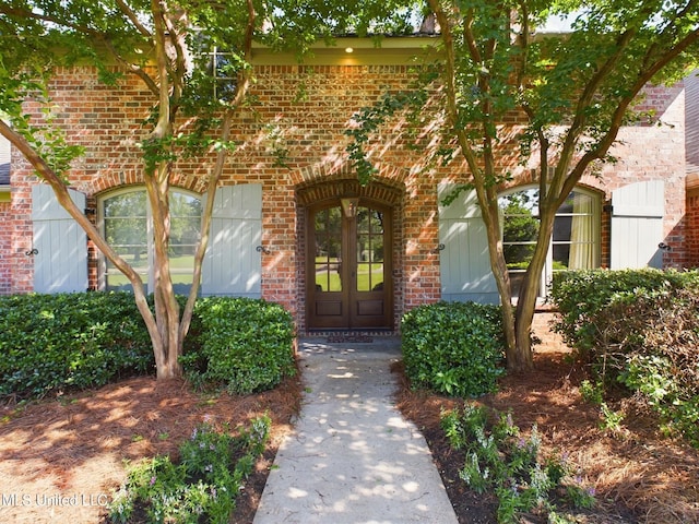 view of exterior entry featuring french doors and brick siding