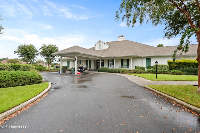 19592 Champion Cir, Gulfport, MS 39503 - view of front of house featuring a chimney, a porch, a front yard, curved driveway, and stucco siding