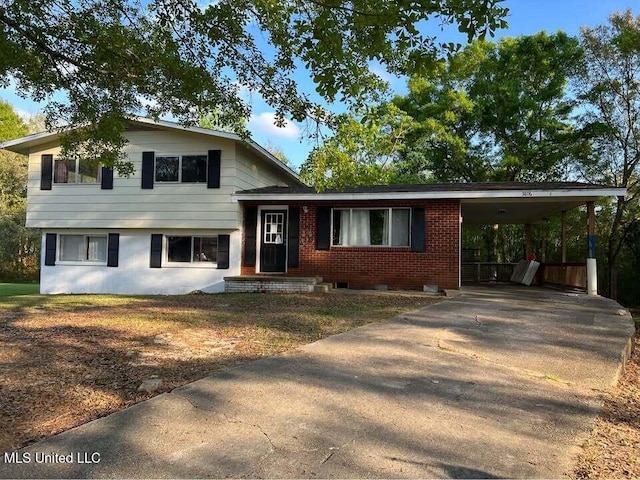 tri-level home with a carport, concrete driveway, and brick siding