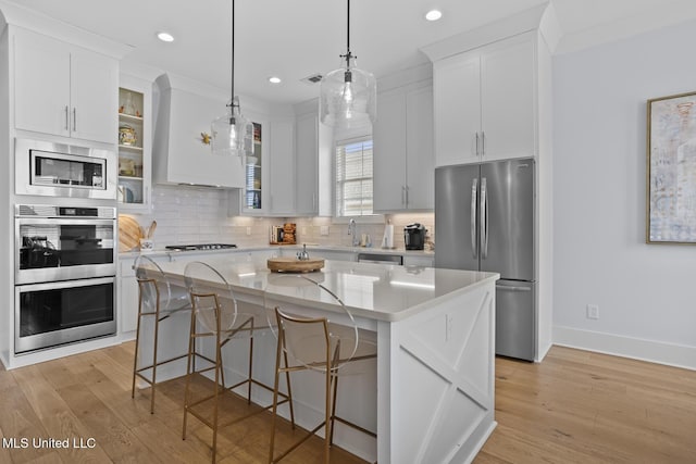 kitchen featuring white cabinetry, a breakfast bar, a center island, and appliances with stainless steel finishes