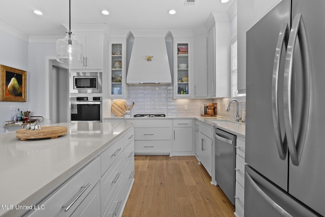 kitchen with premium range hood, sink, decorative light fixtures, stainless steel appliances, and white cabinets