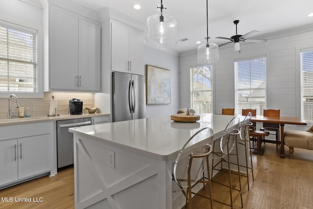 kitchen with appliances with stainless steel finishes, sink, a kitchen island, and white cabinets