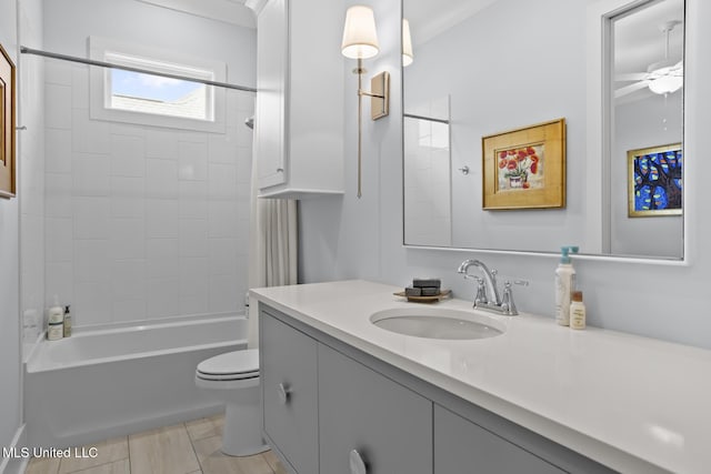 full bathroom with tiled shower / bath, vanity, ceiling fan, and toilet