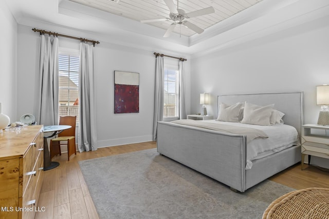 bedroom with ceiling fan, crown molding, light hardwood / wood-style floors, and a tray ceiling