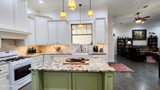 kitchen with dark hardwood / wood-style flooring, white gas range, sink, white cabinets, and a center island