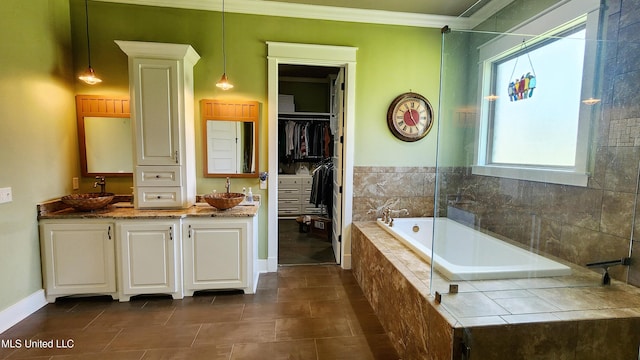 bathroom featuring tile patterned flooring, vanity, ornamental molding, and tiled bath