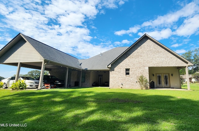 back of property with a carport and a yard