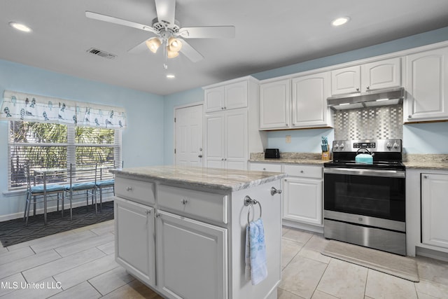 kitchen featuring visible vents, light stone counters, stainless steel electric stove, under cabinet range hood, and white cabinetry