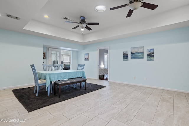 dining area featuring a tray ceiling, visible vents, and baseboards