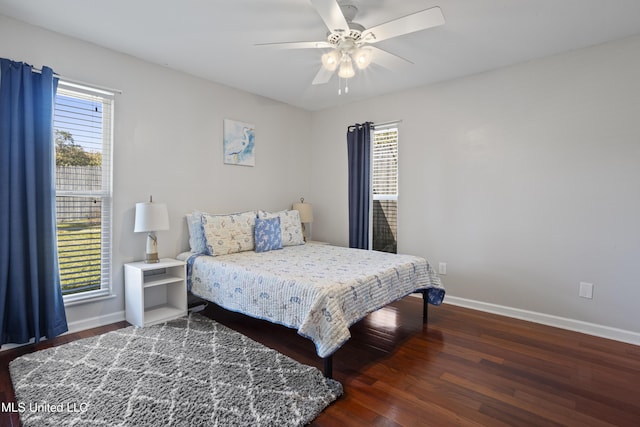 bedroom featuring a ceiling fan, multiple windows, baseboards, and wood finished floors