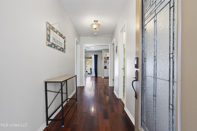 hallway featuring dark wood finished floors and baseboards