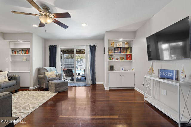 living room featuring built in features, ceiling fan, baseboards, and wood finished floors