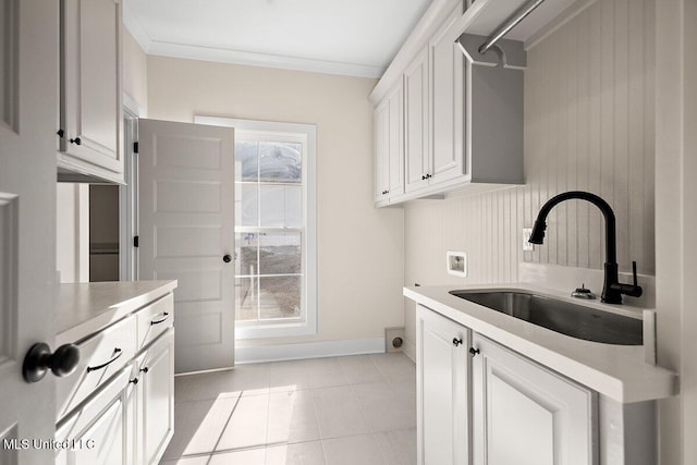 kitchen featuring light countertops, ornamental molding, light tile patterned flooring, a sink, and white cabinetry