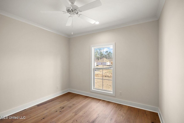 empty room with crown molding, light wood finished floors, and baseboards